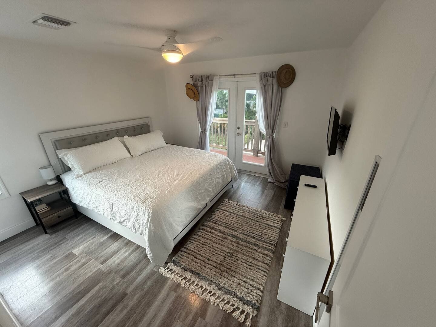 Guest bedroom 1: king bed with white linen and water-view doors