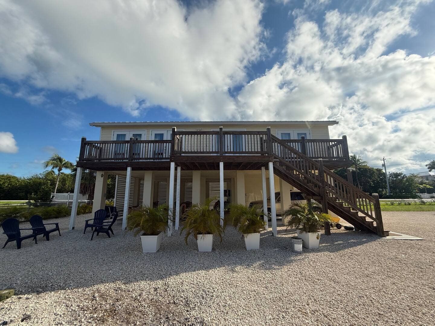 The back of the house, stairs up to the deck and potted palms underneath