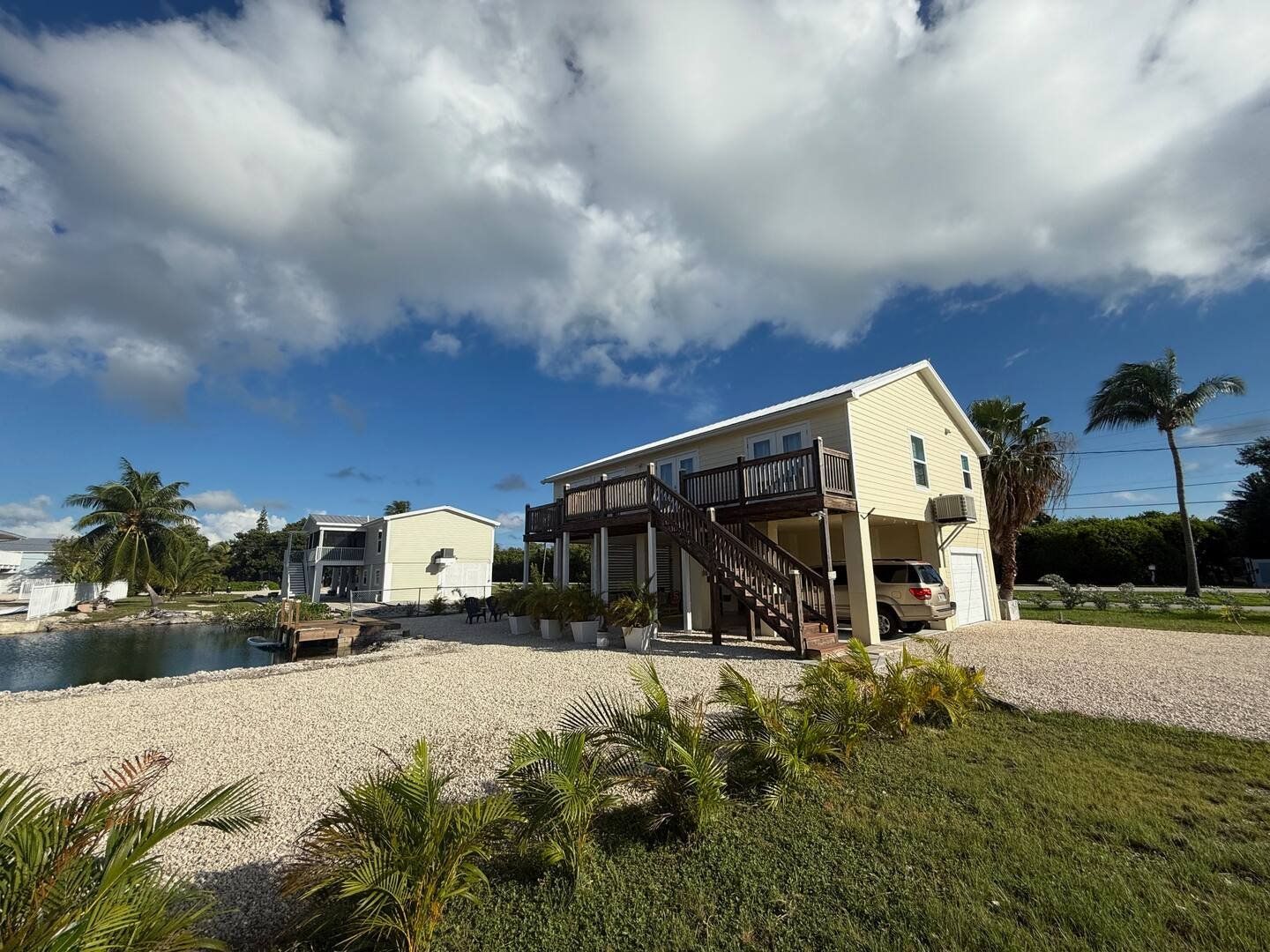 The house under a big Keys sky, with native planting along the shore