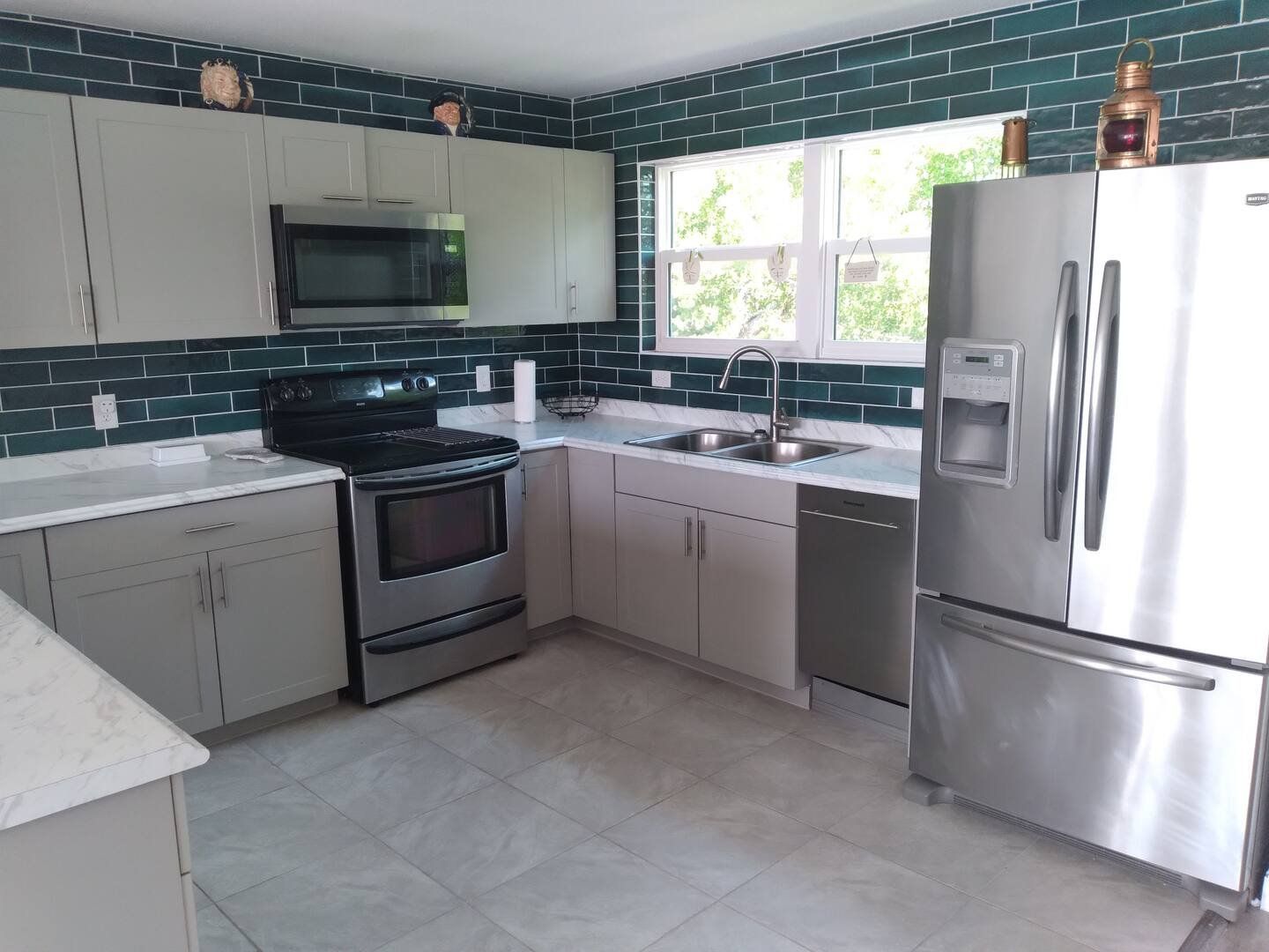 The kitchen with green tiles, stainless appliances and a window over the sink