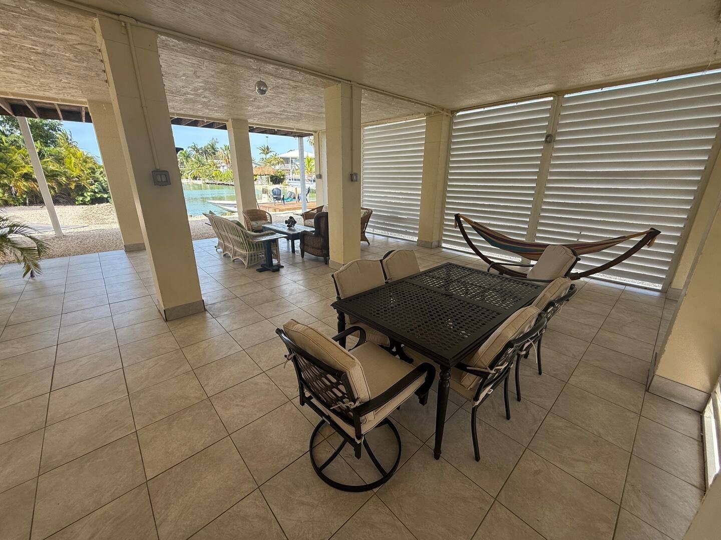 Covered patio under the house with outdoor dining table and a hammock