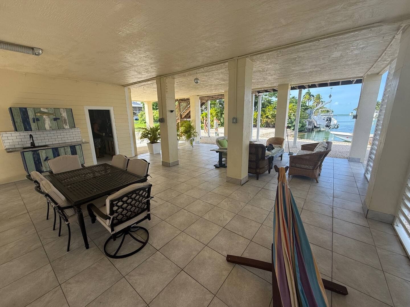 The long covered patio with dining set, hammock and canal beyond
