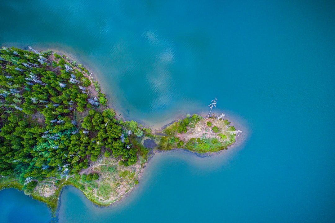Aerial view of a small wooded island ringed by turquoise water